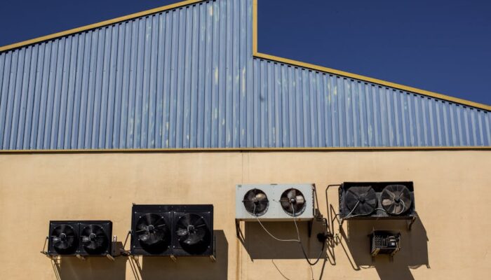 Exterior view of industrial air conditioning units mounted on a warehouse wall under clear blue sky. - Photo by Victor Moragriega on Pexels