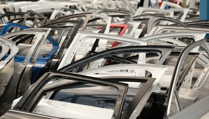 A variety of car doors in different colors arranged in a junkyard setting. - Photo by Aziz Er on Pexels