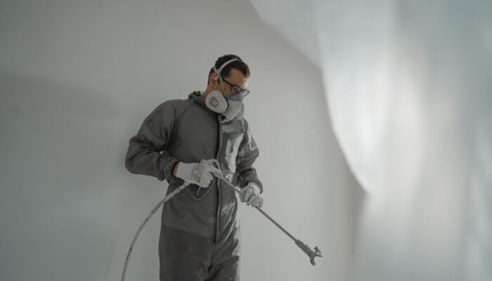 Person in protective gear painting a wall, showcasing house renovation work. - Photo by Tima Miroshnichenko on Pexels
