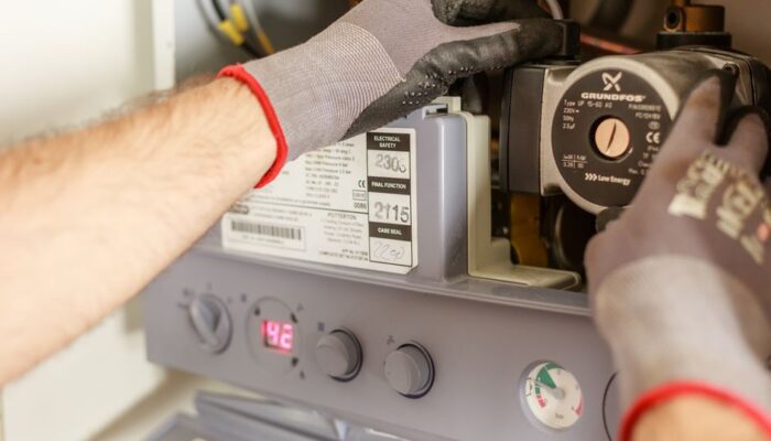 Close-up of hands adjusting a boiler system with precise instrumentation, showing maintenance work. - Photo by Heiko Ruth on Pexels