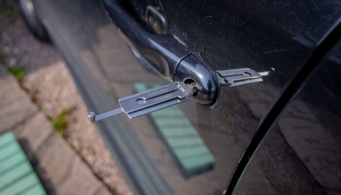 Close-up of a locksmith tool inserted into a car door lock, demonstrating security access. - Photo by My Car Key Hero on Pexels