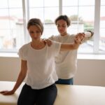A therapist assists a woman with arm stretching during a physical therapy session in a bright, indoor setting. - Photo by Yan Krukau on Pexels