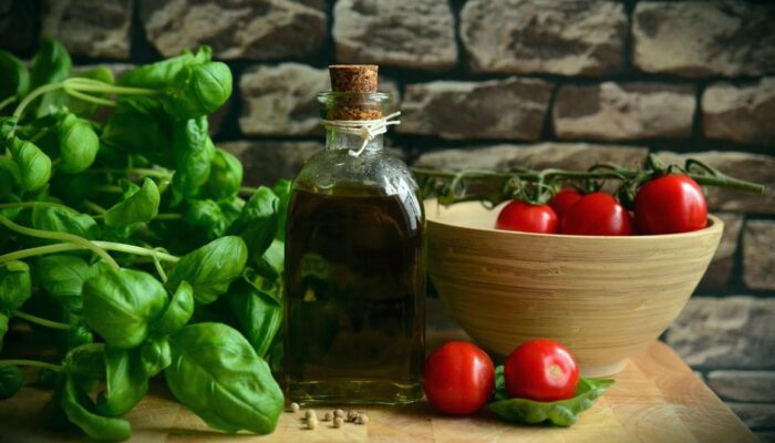A rustic arrangement of fresh basil, ripe tomatoes, and olive oil on a wooden surface. - Photo by Pixabay on Pexels